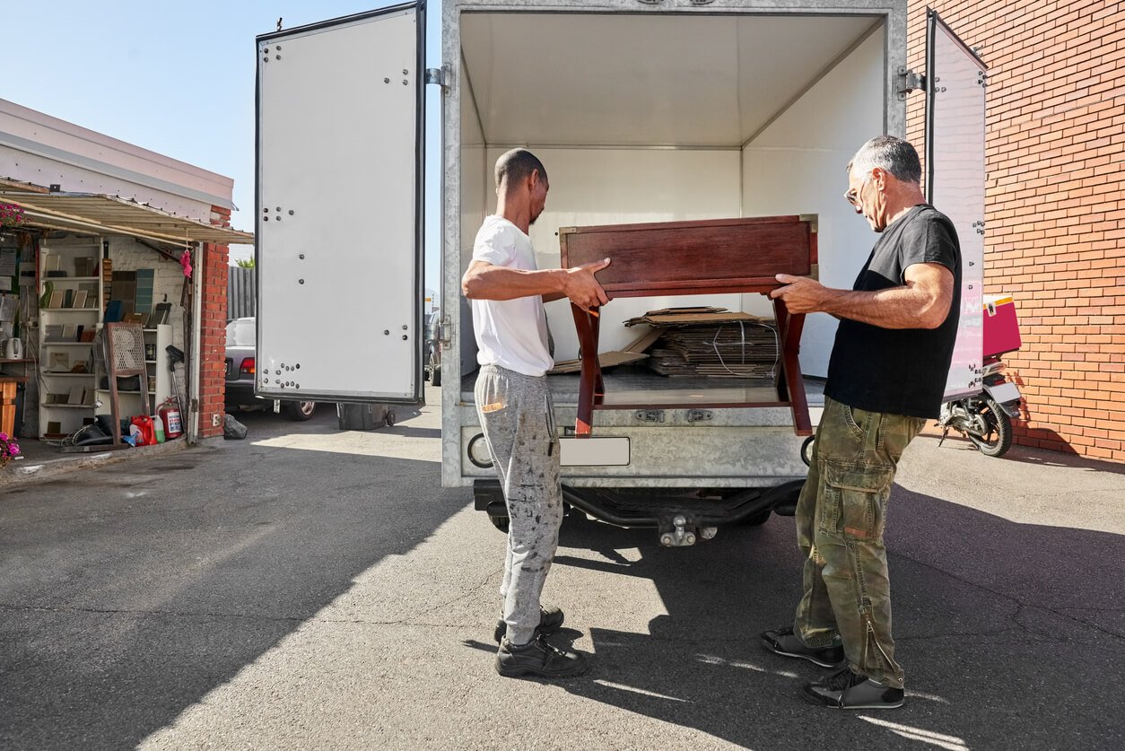 Two professional movers carrying a junk furniture into a transport van in Pompano Beach, FL